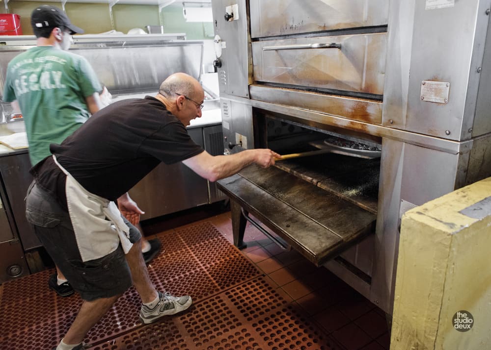 Sliding a pizza into the deck oven with a long peel