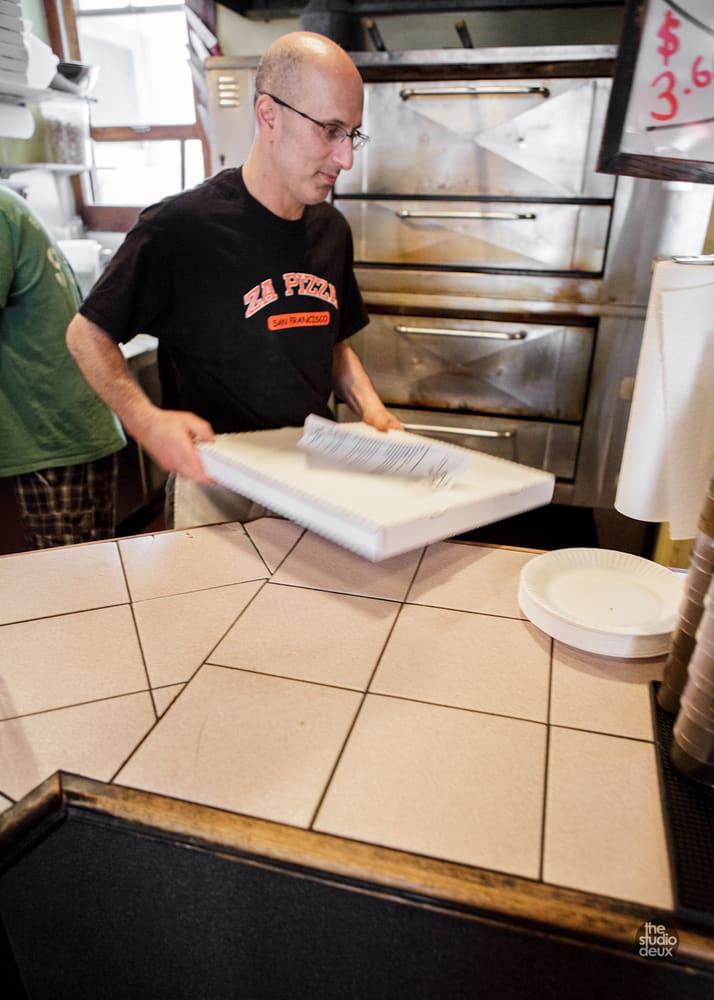 Boxing a pizza at the counter in a ZA PIZZA shirt